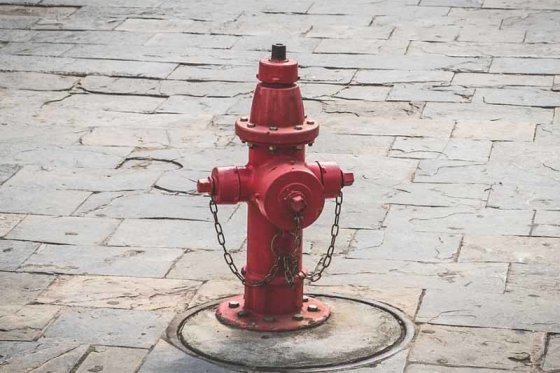 A red outdoor fire hydrant on a paved surface, one of the common water supply points
