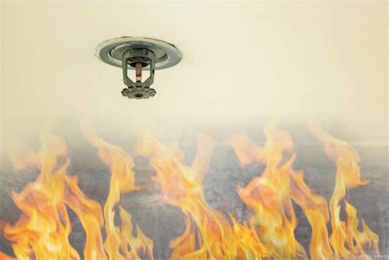 Close-up of a pendent fire sprinkler head above flames